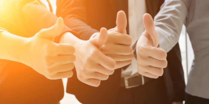 A group of business people giving a thumb up gesture