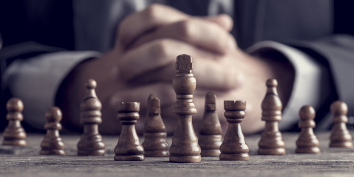 Chess figurines and a businessman in the background, symbolizing teamwork, appointment