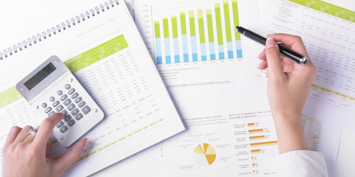 Woman making calculations, financial reports and calculator in front of her