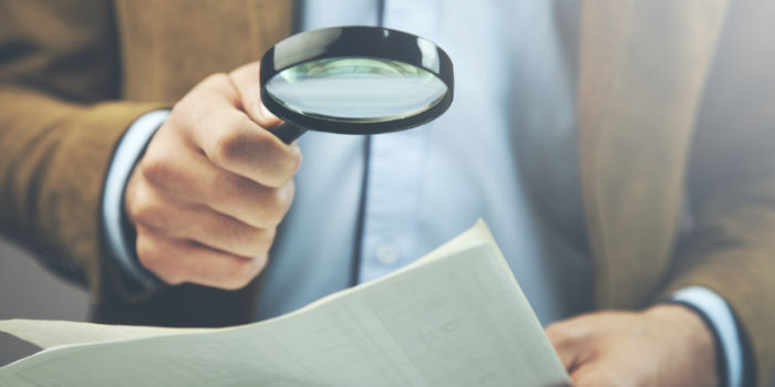 A businessman holding a document and magnifying glass