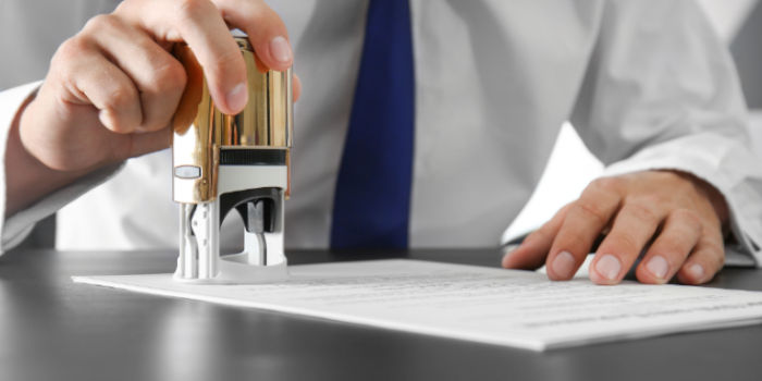 A businessman placing a stamp on a document, symbolizing approval